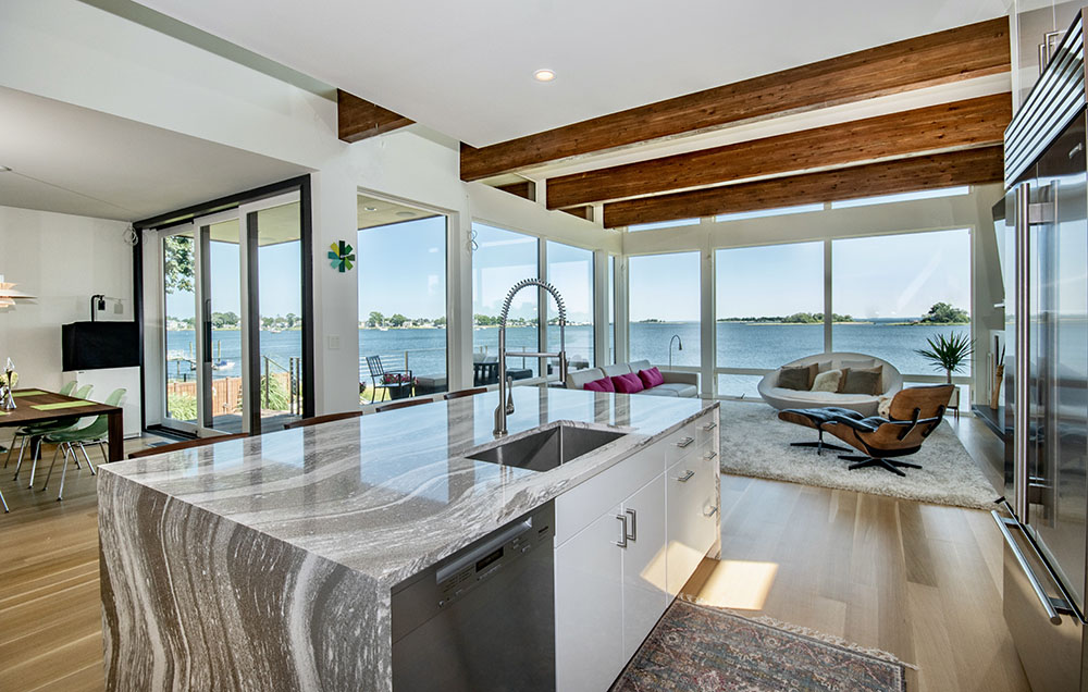 Beautiful kitchen and living room with big windows and a view of the water